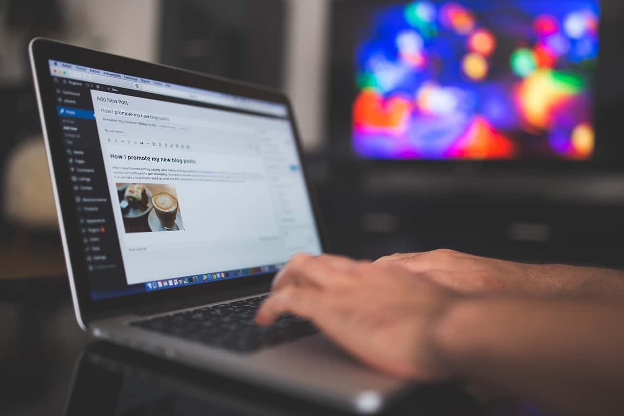 Image showing a pair of hands writing on a laptop keyboard. Wordpress backend is on the screen.